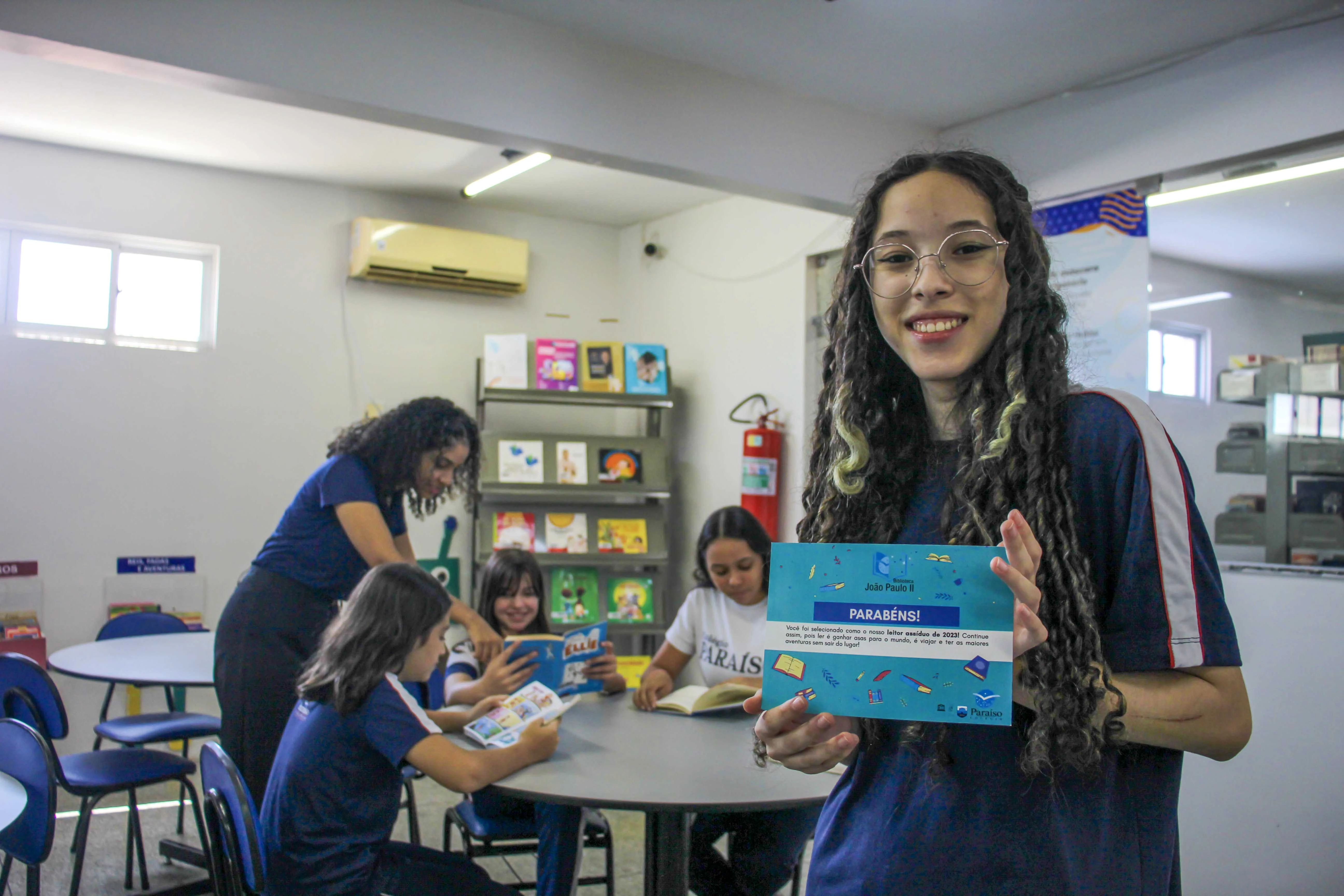 alunos sentados estudando com livros da biblioteca