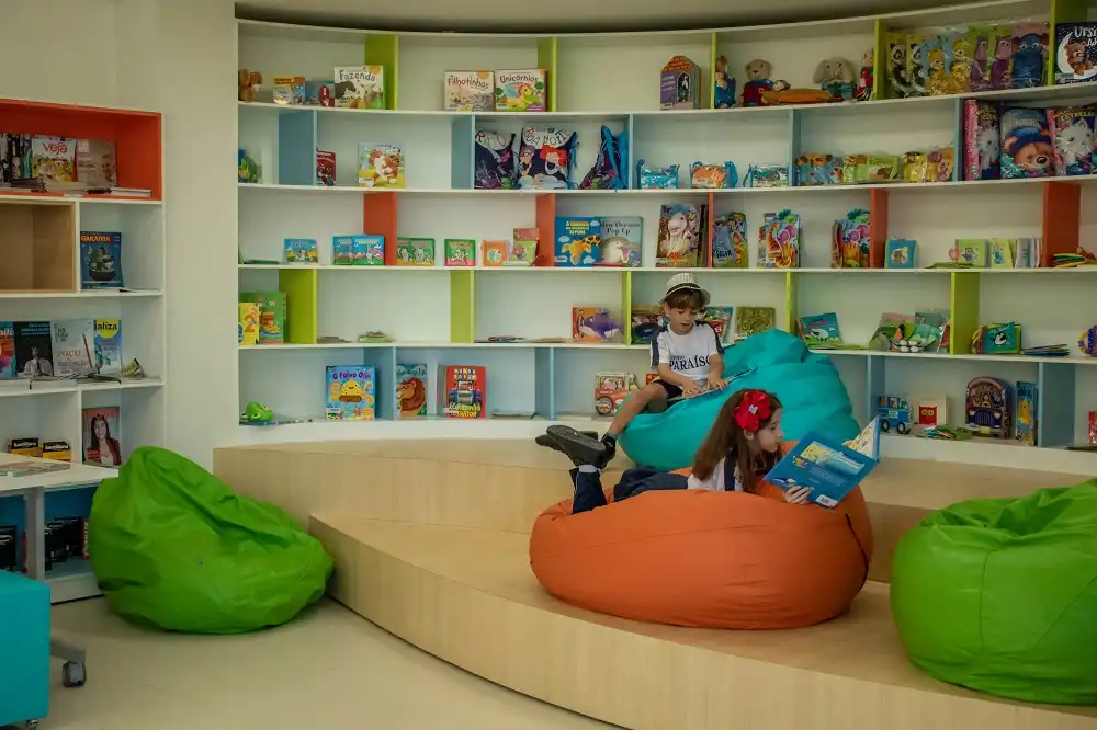 alunos lendo sentados em almofadas na biblioteca